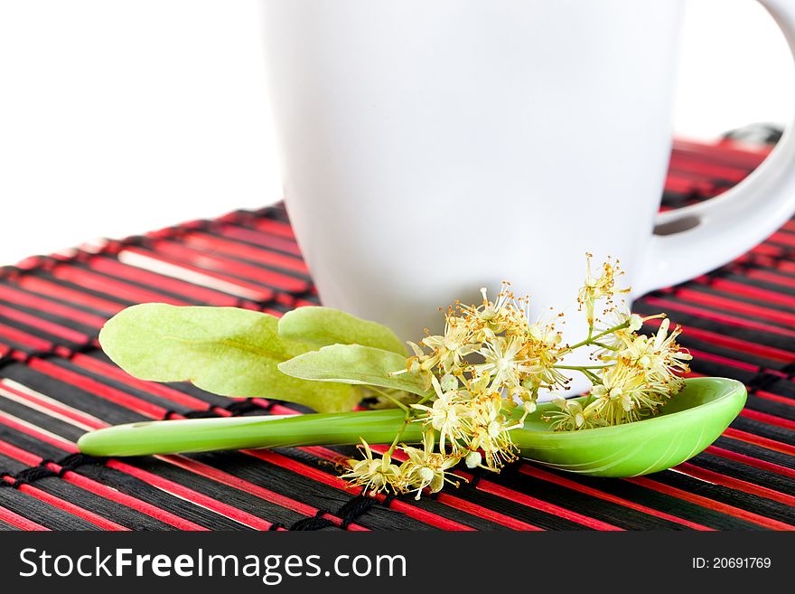 The flower of a linden lying in a green spoon about cup (isolated). The flower of a linden lying in a green spoon about cup (isolated)