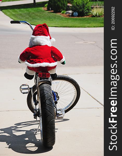Santa Clause during the off season cruising on his chopper style bicycle. Stuffed Santa doll sitting on a bicycle. Santa Clause during the off season cruising on his chopper style bicycle. Stuffed Santa doll sitting on a bicycle.