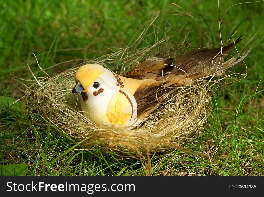 Toy bird in the nest, on the green grass, close-up