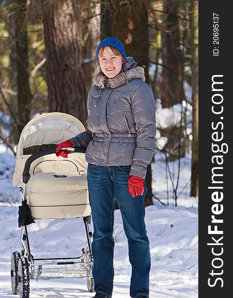 Mother walking with baby carriage in winter