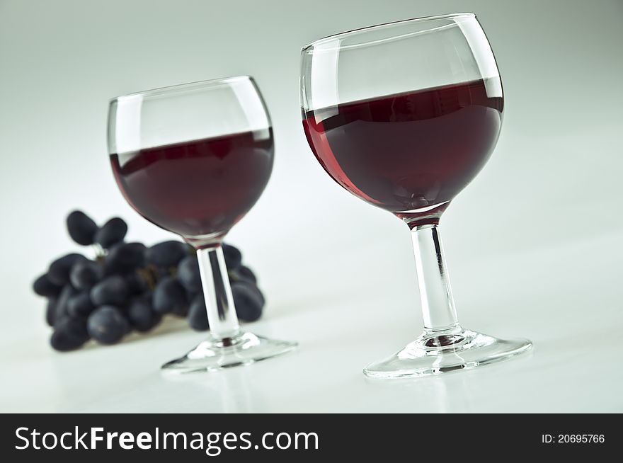 Two glasses of red wine and some grapes. Two glasses of red wine and some grapes