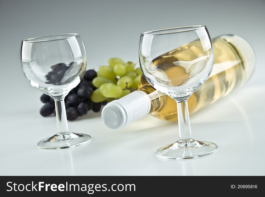 Bottle of white wine and two empty glasses. Bottle of white wine and two empty glasses