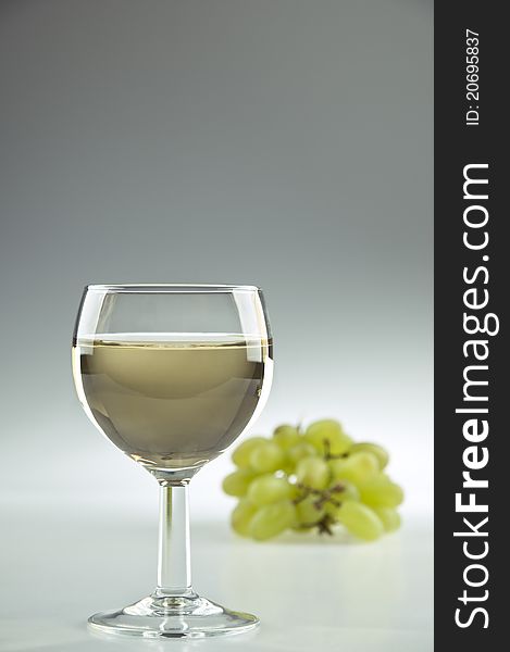 Glass of white wine and grapes in the background. Glass of white wine and grapes in the background