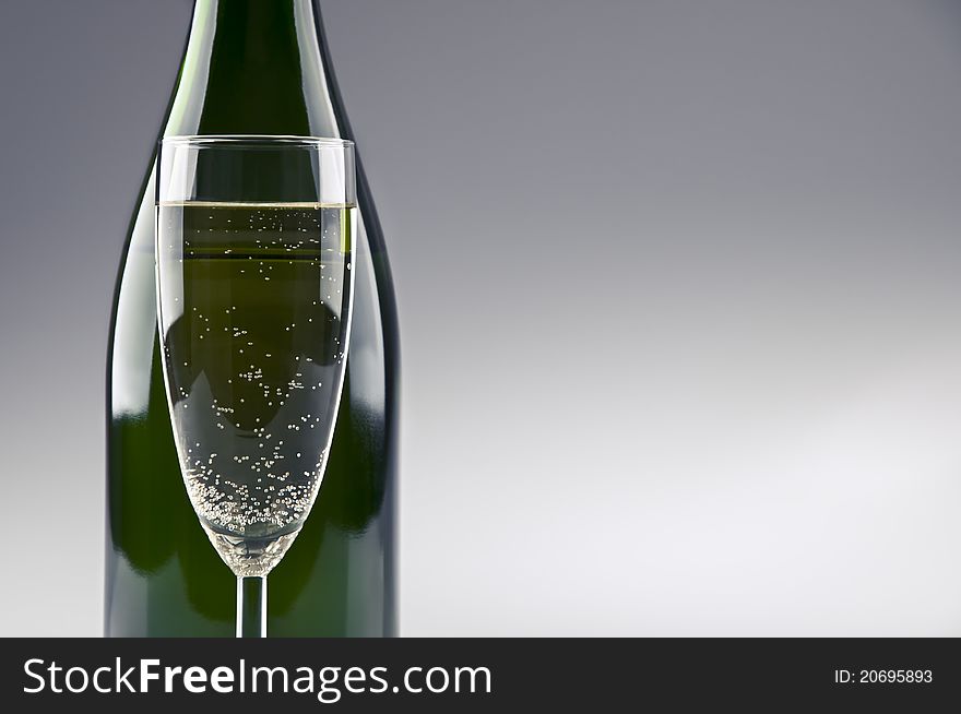 A champagne bottle and glass standing in front