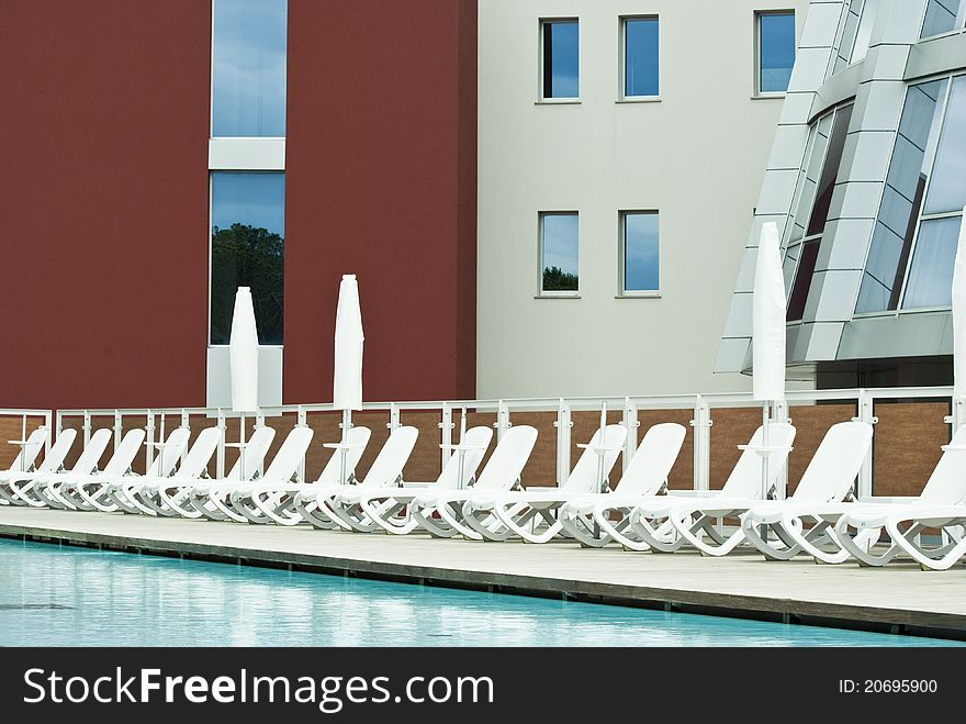A modern hotel and a luxury swimming pool with all the deck-chairs ready. A modern hotel and a luxury swimming pool with all the deck-chairs ready
