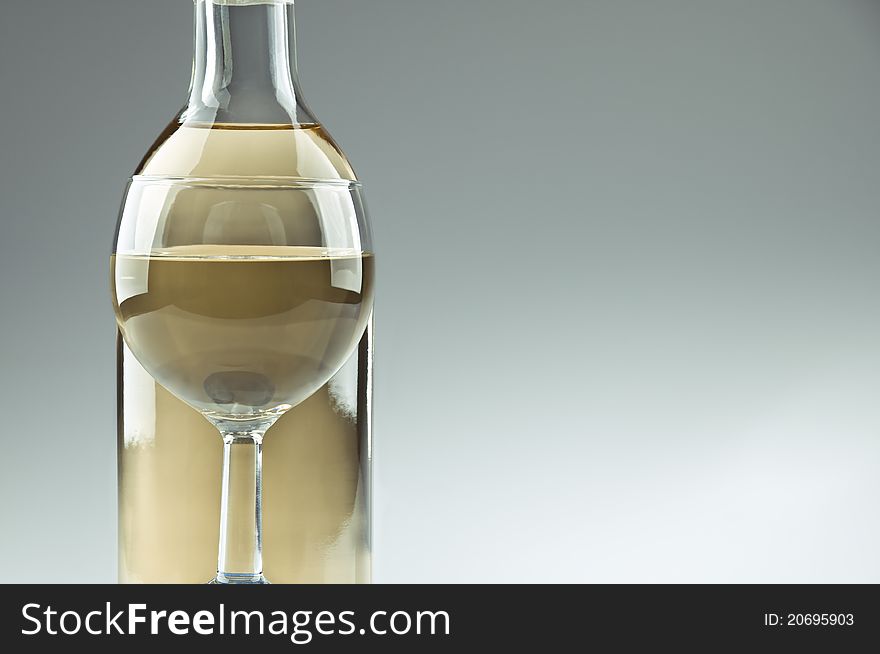 A bottle and a glass of white wine, glass in front of the bottle