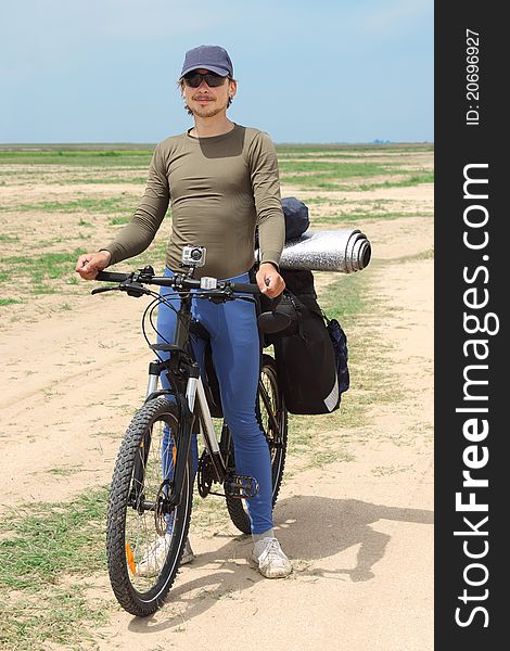 Bicycle tourist standing on road, blue sky and horizon