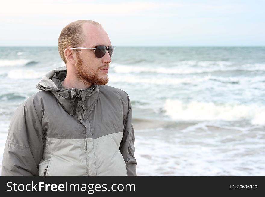 Portrait of man with beard in sunglasses near sea