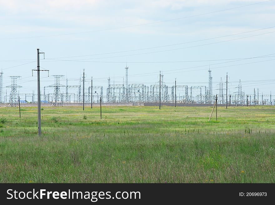 Transformation station and power lines on green field in Russia