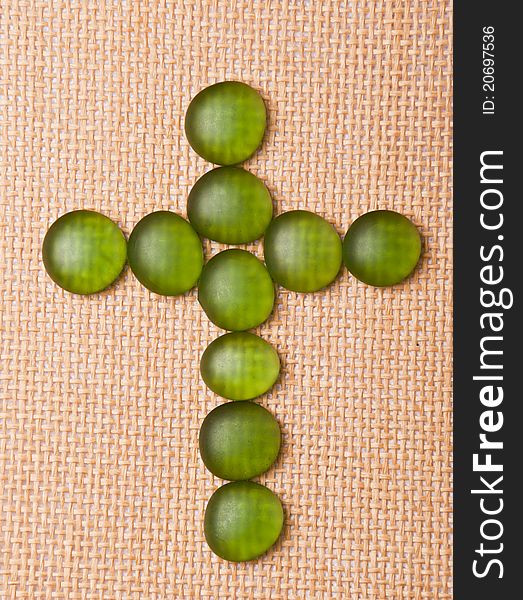 Glass crucifix on a straw background.