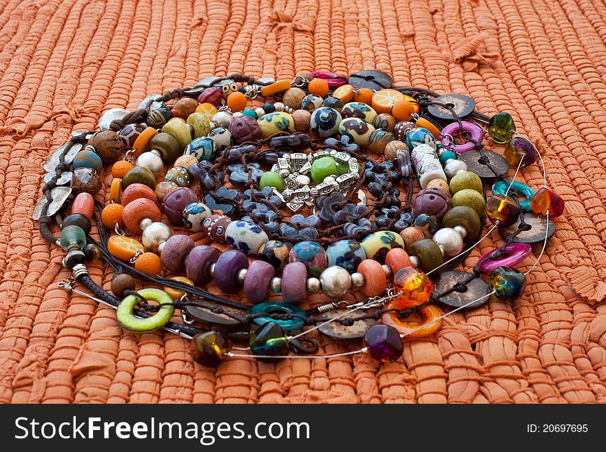 Handmade varicoloured beads in a spiral on a orange background