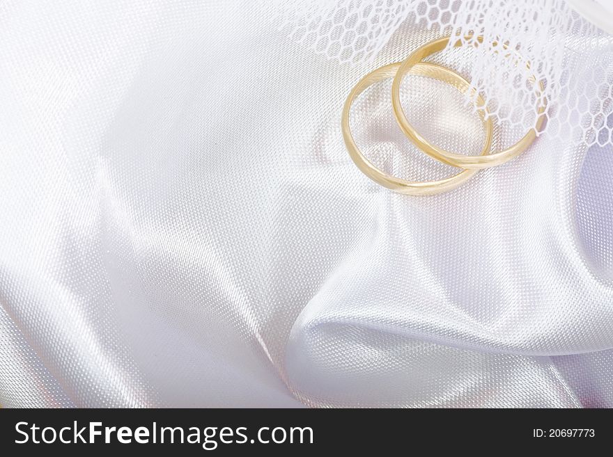 Two Gold Wedding Rings On A White