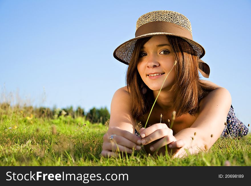 Young nice attentive woman lies on green grass