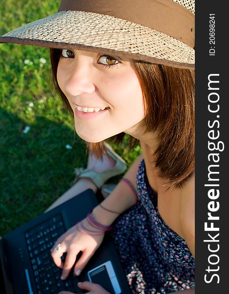 Smiling beautiful woman laying on grass and working on laptop