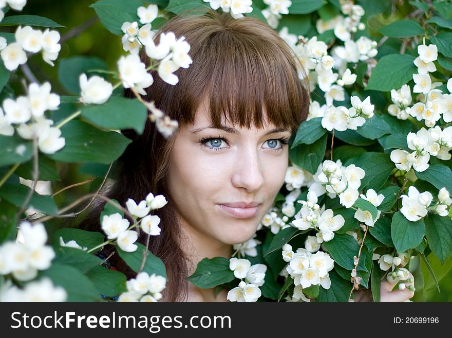 Closeup portrait of a beautiful girl standing among flowers