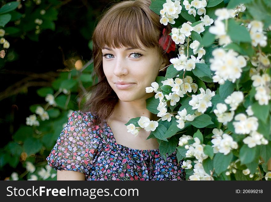 Closeup portrait of a beautiful girl standing among flowers