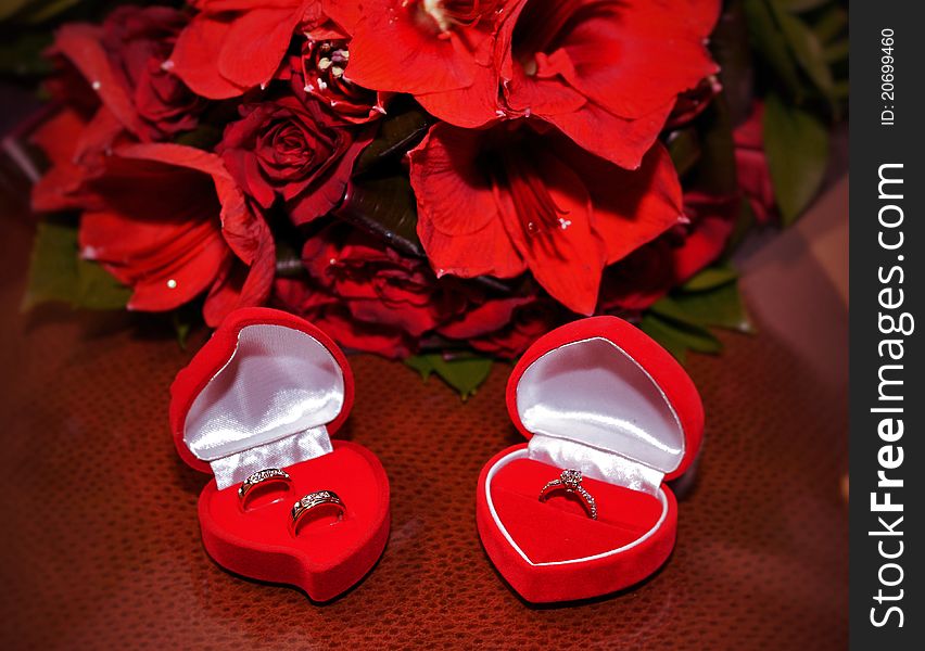 ROM/Wedding rings displayed on a table with red roses behind. ROM/Wedding rings displayed on a table with red roses behind.