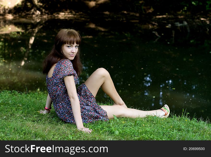 Beautiful girl sitting on bank of a river