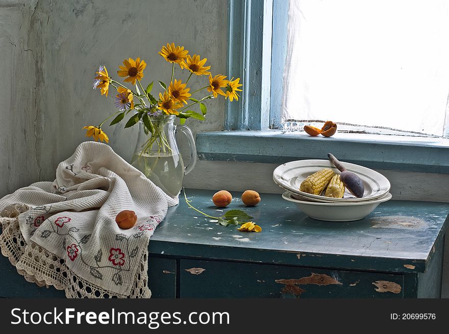 A bouquet of yellow flowers and boiled corn are in a dish. A bouquet of yellow flowers and boiled corn are in a dish