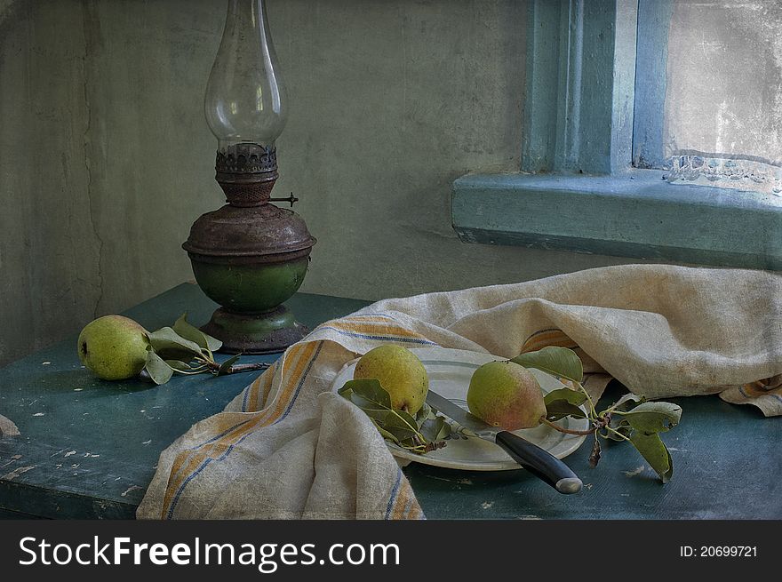 Three pears and kerosene lamp on a table