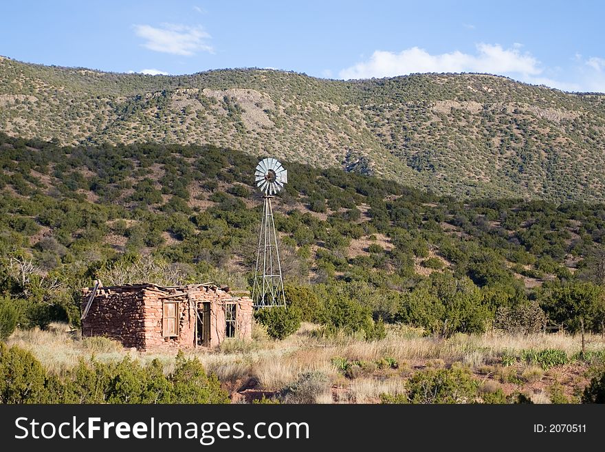 An old homestead and windmill in the foothills of a mountain range. An old homestead and windmill in the foothills of a mountain range