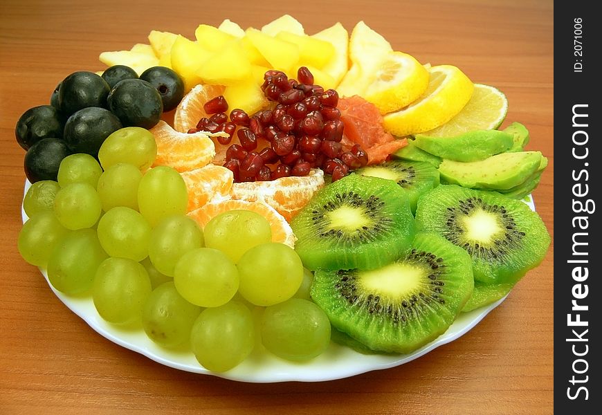 Grapes, orange, pomegranate, grapefruit, mango, avocado, apple, kiwi and slices of lemon. Grapes, orange, pomegranate, grapefruit, mango, avocado, apple, kiwi and slices of lemon