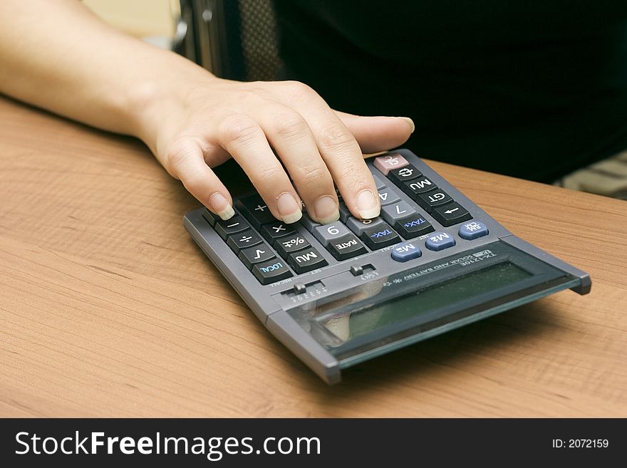 Girl doing account with a solar calculator in a business office. Girl doing account with a solar calculator in a business office