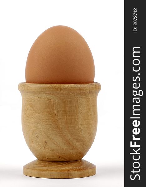 Brown egg sitting in a wooden egg cup.