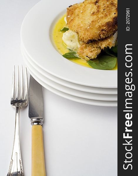 Chicken schnitzel, baked with potato mash, baby spinach and beure blanc sauce. Portrait view with antique knife and fork. Chicken schnitzel, baked with potato mash, baby spinach and beure blanc sauce. Portrait view with antique knife and fork.