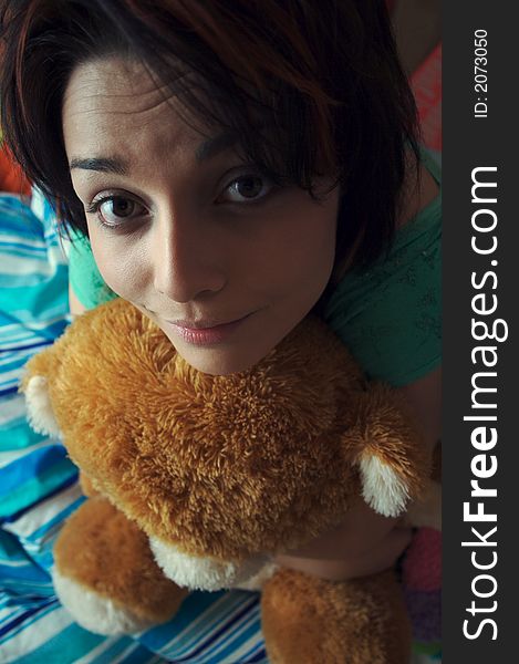 Young girl with her toy bear sitting on the bed. Young girl with her toy bear sitting on the bed