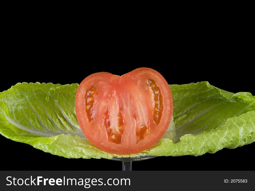 A sliced red tomato with romaine lettuce. A sliced red tomato with romaine lettuce