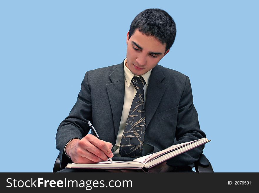 Young businessman writing a book isolated on blue