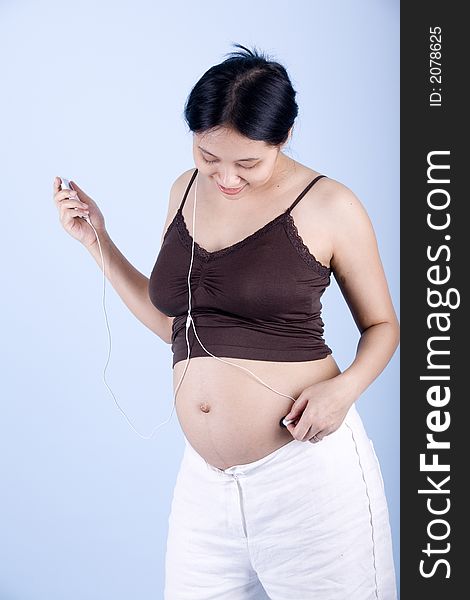 Isolated Pregnant woman listening to classical music over blue background. Isolated Pregnant woman listening to classical music over blue background