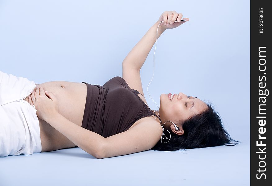 Isolated Pregnant woman listening to classical music over blue background. Isolated Pregnant woman listening to classical music over blue background