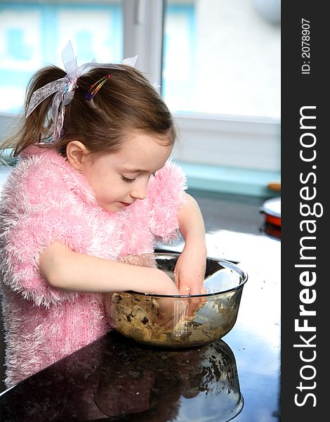 Young girl mixing food ingredients in a bowl with her hands. Young girl mixing food ingredients in a bowl with her hands