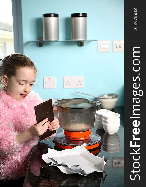 Young girl breaking a chocolate bar in bits before mixing. Young girl breaking a chocolate bar in bits before mixing