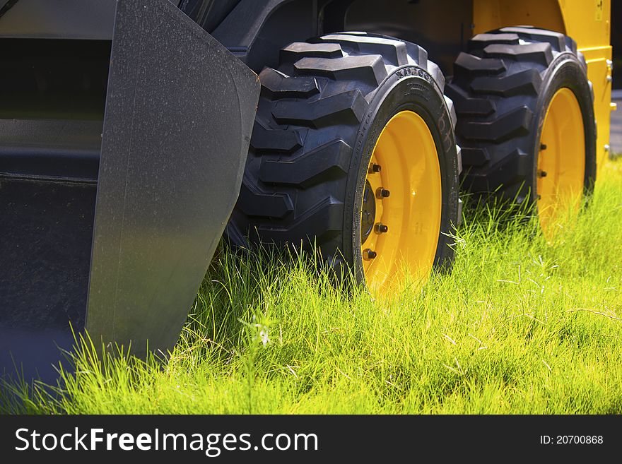 Big yellow black tractor wheels on green grass