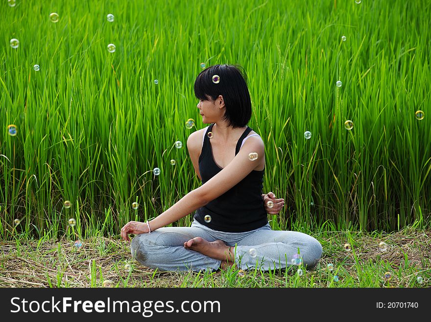 Girl practicing yoga in paddy field