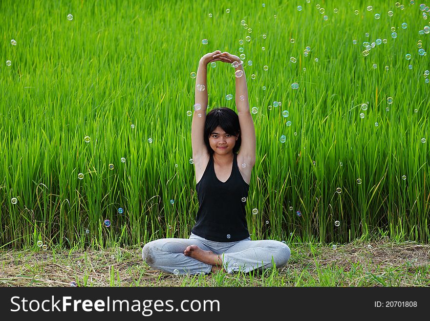 Girl practicing yoga in paddy field