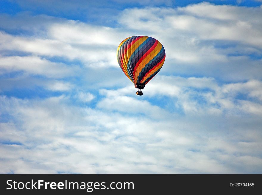 A colorful hot air balloon on a backdrop of white clouds and blue sky. A colorful hot air balloon on a backdrop of white clouds and blue sky