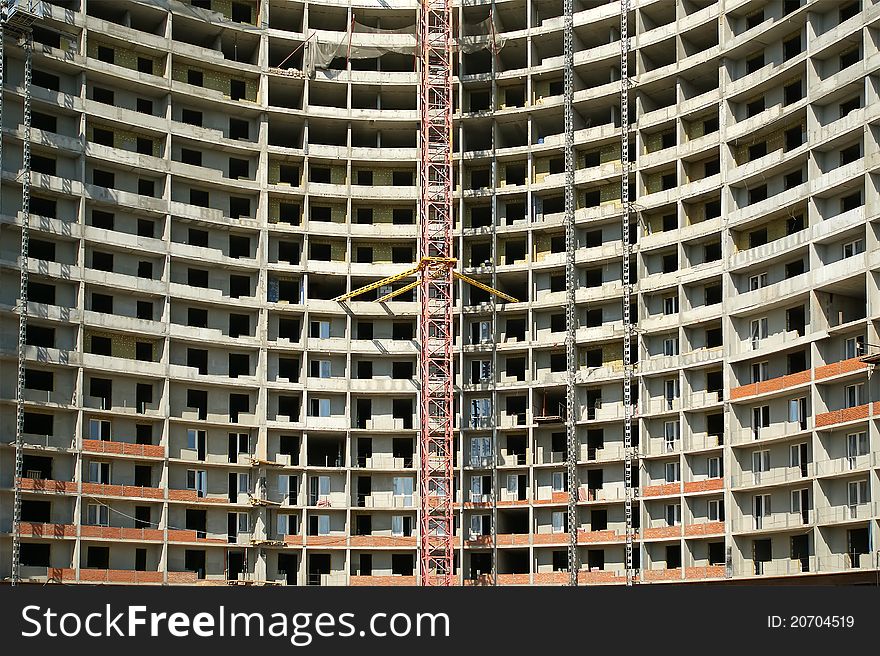 Building crane at the background of a multi-storey building under construction