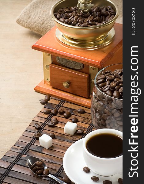 Cup of coffee and grinder with roasted beans on wooden. Cup of coffee and grinder with roasted beans on wooden