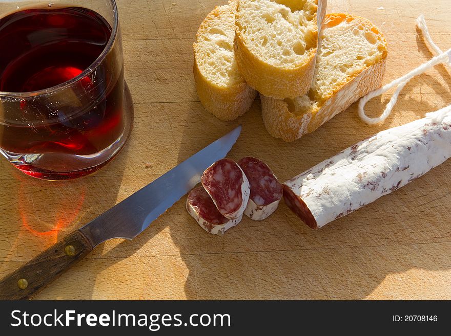 Salami wooden board with bread and a glass of red wine. Salami wooden board with bread and a glass of red wine