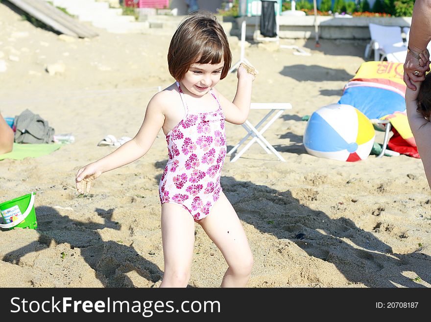 Beautiful child girl throwing sand on the beach. Beautiful child girl throwing sand on the beach