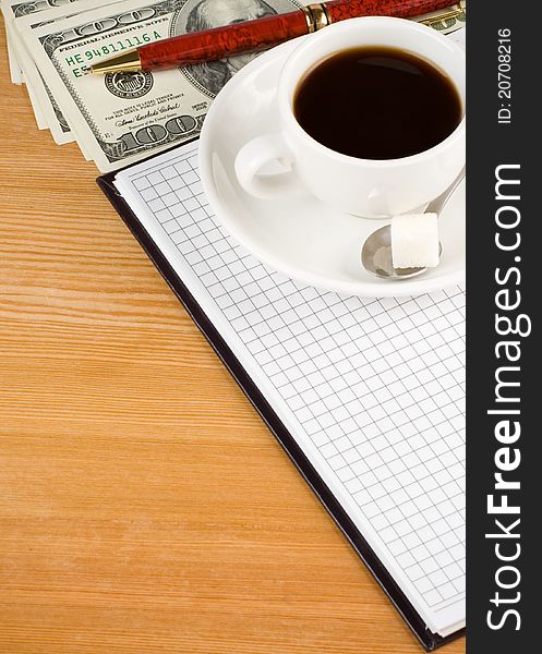 Cup of coffee and notebook with dollar on wood table