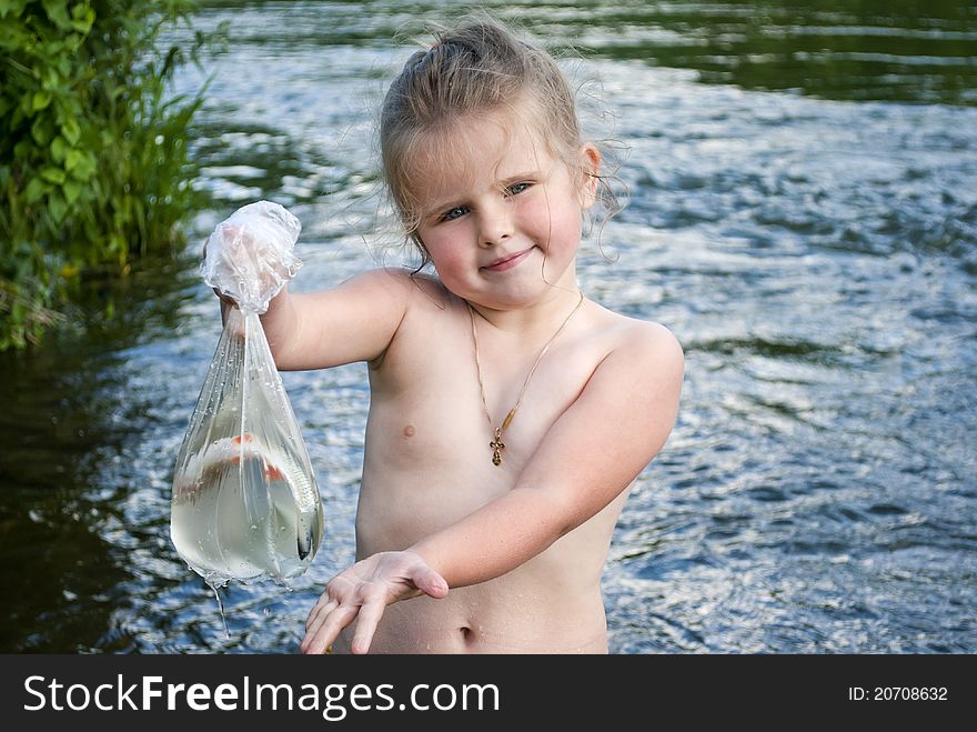 The child on the nature holds in hands fish which has caught in the river. The child on the nature holds in hands fish which has caught in the river