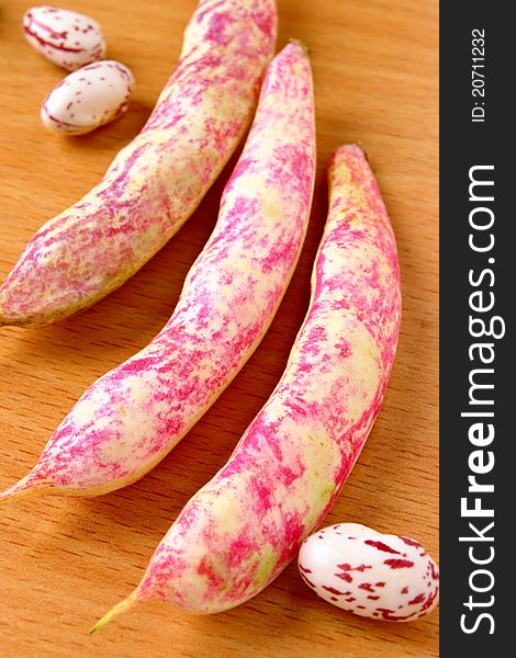 Raw beans in red on a wooden table. Raw beans in red on a wooden table