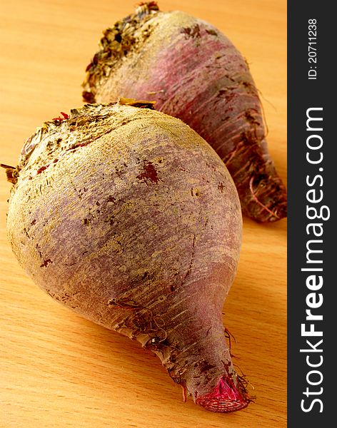 On a wooden table, two red beets. On a wooden table, two red beets