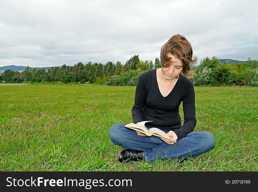 Young woman reading a book on the green grass. Young woman reading a book on the green grass