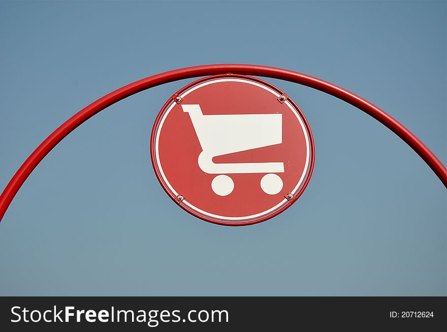Red shopping cart sign with blue sky background